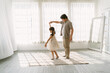 Portrait of Asian father and little daughter in beautiful skirt dancing waltz at home. Happy chinese or japanese father spending free time with cute daughter, enjoy weekend in living room together.