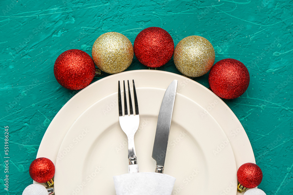 Table setting with Christmas balls on green background, closeup