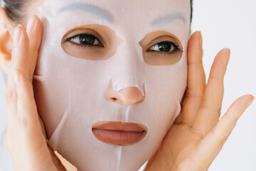 Sticker - Young woman applies white sheet mask to her face