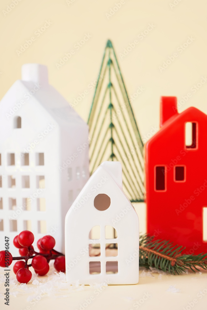 House shaped candle holders with Christmas branches on beige background