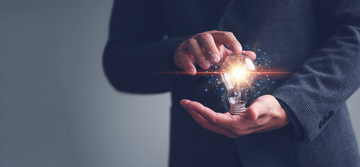 Poster - Innovation through ideas and inspiration ideas. Human hand holding light bulb to illuminate, idea of creativity and inspiration concept of sustainable business development.