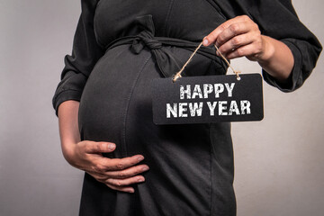 Happy New Year. Pregnant woman is holding a blackboard with a text