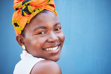 Black woman, face portrait and happy smile with makeup, beauty and fashion scarf on her head with blue wall background. Young female with natural cosmetics, happiness or smiling outdoor with mockup