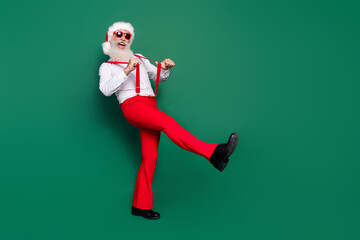 Poster - Full length photo of cheerful positive senior guy wear red trousers dance nightclub go step empty space isolated on green color background