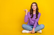 Full length portrait of cheerful nice person sit floor look direct finger empty space isolated on yellow color background