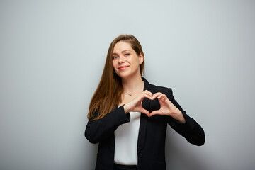 Wall Mural - Smiling business woman in black suit holding heart figure with fingers, isolated portrait.