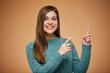 © Yuriy Shevtsov - Smiling young woman pointing fingers up. Isolated advertising portrait on yellow, orange background.