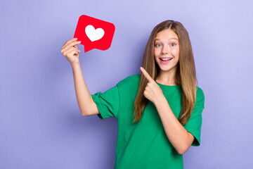 Sticker - Photo of positive cute lady wear green stylish clothes arm direct red card heart symbol empty space isolated on purple color background