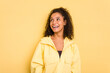 © Asier - Young Brazilian curly hair cute woman isolated on yellow background relaxed and happy laughing, neck stretched showing teeth.