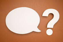 White Speech Bubble And A White Question Mark On A Brown Background