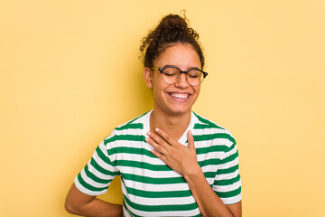 Young Brazilian curly hair cute woman isolated on yellow background laughing keeping hands on heart, concept of happiness.