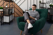 © Ivan Traimak - caucasian businesswoman with a short haircut sits in an emerald easy chair in the middle of the office