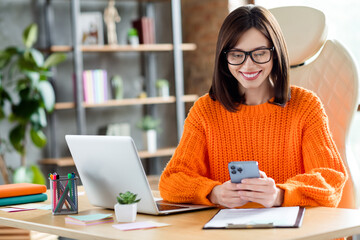 Poster - Photo of positive attractive lady wear orange sweater smiling connecting clients modern device indoors workshop workplace workstation