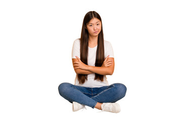 Young asian woman sitting on the floor cutout isolated suspicious, uncertain, examining you.