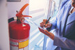 woman worker inspection chemical Fire extinguisher and fire hose. writing on monthly check document. Selected focus	