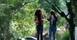 Two diverse young women laughing together while walking outside in street