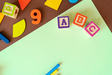 Wall Mural - Wooden kids toys on colourful paper. Educational toys, blocks, pyramid, pencils, numbers, rainbow. Toys for kindergarten, preschool or daycare. Copy space for text. Top view. Back to school background