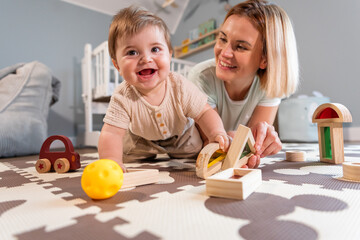 Loving family mom and baby boy playing together toys on floor in child room