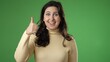© Robert Peak - Portrait of excited, surprised smiling pretty young hipster woman 20s gives thumbs up smiling isolated on green screen background studio