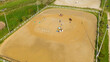 Aerial view of three horsemen. A riding field with fence and obstacles to train horses. In this sports facility, tournaments and horse racing courses are organized. The sports center is in the nature.