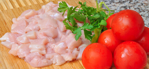 Wall Mural - Fresh uncooked chicken meat breast pieces, ready to cook, with tomato and parsley