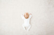 Baby in white bodysuit crawling on knee and arms on light beige home carpet. 5 to 6 months old infant development. Top down view.