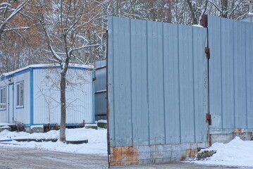 Poster - one large gray open metal gate covered in white snow on a winter street