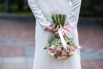 Wall Mural - The bride in a white wedding dress is holding a bouquet of white flowers - peonies, roses. Wedding. Bride and groom. Delicate welcome bouquet. Beautiful decoration of weddings with leaves