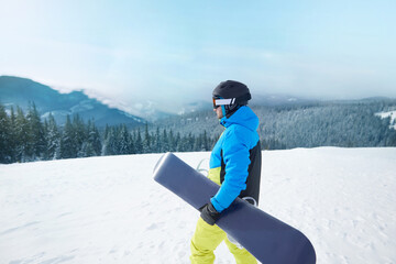 Wall Mural - Snowboarder Of Man At Ski Resort On The Background Blue Sky,  Hold Snowboard. Wearing Ski Glasses. Ski Goggles  With The Reflection Of Snowed Mountains