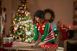 © SuperStock - Serious young woman wrapping Christmas gifts in front of a Christmas Tree in her living room.