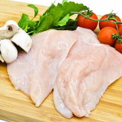 Wall Mural - Fresh uncooked chicken meat breast pieces, ready to cook, with tomatoes greens and mushrooms