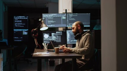 Software developer typing source code on laptop and multiple monitors, using programming language to create firewall security server. Male coder developing database cloud computing.
