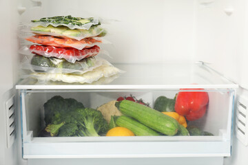 Vacuum bags with different vegetables in fridge, space for text. Food storage