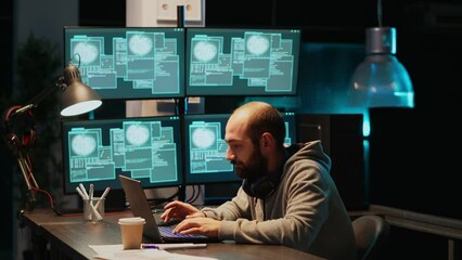 Cyber criminal celebrating hacking success in office at night, working with multiple monitors to steal password. Cheerful hacker with hidden identity feeling pleased about achievement.