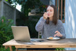 © wattana - Satisfied caucasian woman eating a piece of cake and drinking coffee in outdoor coffee shop.