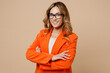 © ViDi Studio - Young successful employee business woman corporate lawyer wear classic formal orange suit glasses work in office look camera hold hands crossed folded isolated on plain beige color background studio.