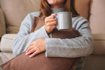 Wall Mural - Closeup image of a young woman drinking hot coffee and relaxing at home