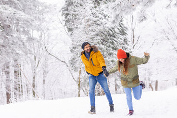 Couple having fun running in the snow while on winter vacation