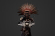 Ancient witch with plumed headdress and staff with skull. High quality photoShot of aztec witch dressed in ceremonial headdress holding staff with skull.