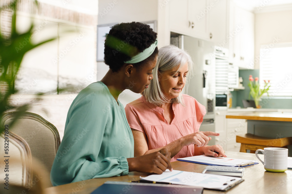Senior caucasian woman talking with african american female financial advisor