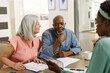 © WavebreakMediaMicro - Senior diverse couple talking with african american female financial advisor