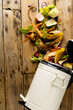 Vertical image of organic fruit and vegetable food waste spilling from open kitchen composting bin