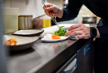 chef cooking slice salmon fish and shrimp with salad on kitchen