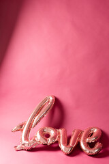 Vertical of metallic pale pink love text balloon on pink background with copy space