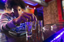 Drunk African American Man Sitting At The Bar With Shots Glasses In A Bar