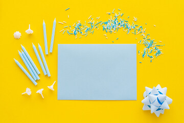 Wall Mural - top view of empty greeting card near candles and blue sprinkles on yellow background.