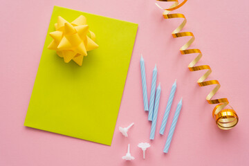 Wall Mural - top view of greeting card near serpentine and festive candles on pink background.