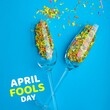 Composition of april fools day text over champagne glasses with confetti