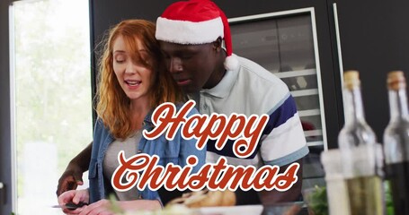 Canvas Print - Animation of christmas greetings text over diverse couple in kitchen at christmas