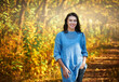 © Denys Kurbatov - Smiling young brunette posing in park on background of trees with orange leaves